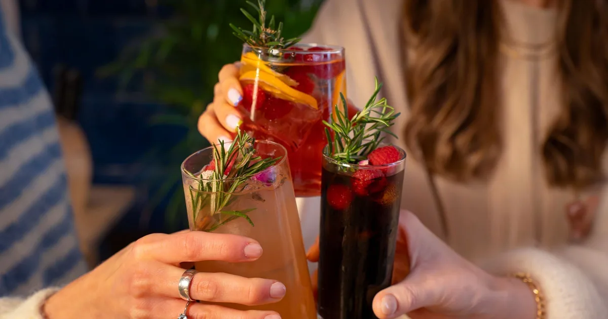 Trzy kolorowe drinki bezalkoholowe z owocami i rozmarynem wznoszone do toastu
