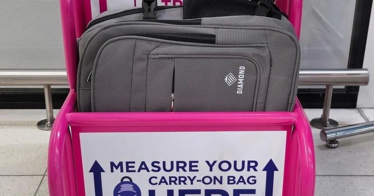 Szary plecak Diamond włożony do lotniskowej ramki do mierzenia bagażu podręcznego z napisem Measure your carry-on bag here