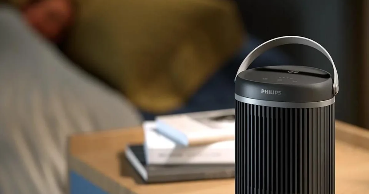 Ciemnoszary termowentylator Philips CX3120 na szafce nocnej obok łóżka, w tle śpiąca osoba