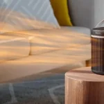 Termowentylator ceramiczny Philips CX3120 na drewnianym stoliku obok sofy, strumień ciepłego powietrza nad salonem