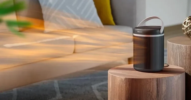 Termowentylator ceramiczny Philips CX3120 na drewnianym stoliku obok sofy, strumień ciepłego powietrza nad salonem