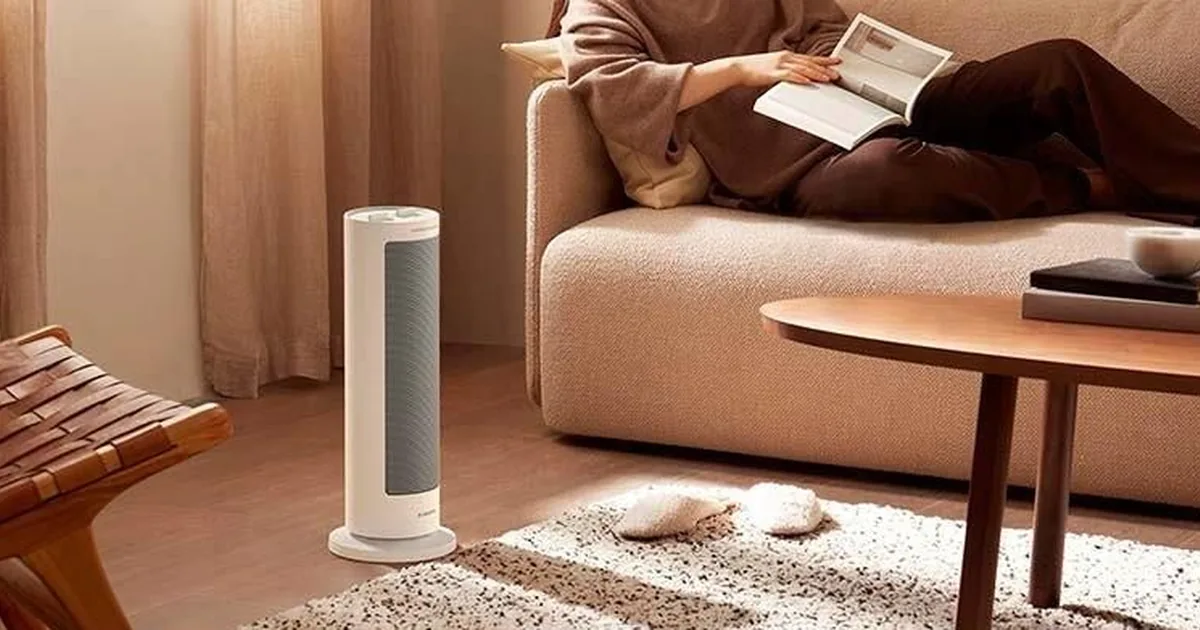 Biały kolumnowy termowentylator Xiaomi obok sofy, na której kobieta czyta książkę